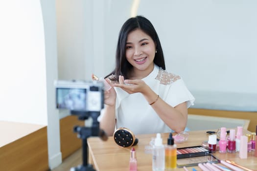 online trading business, a beautiful young woman working independently at home reviewing cosmetic products through the camera to customers to increase their interest in making a purchase decision.