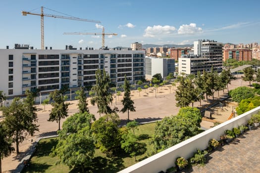 New houses are being built in Gorg, Barcelona in Spain with construction cranes on blue sky on a sunny warm summer day. Concept of new luxury comfortable areas in Europe.