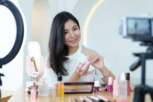 online trading business, a beautiful young woman working independently at home reviewing cosmetic products through the camera to customers to increase their interest in making a purchase decision.