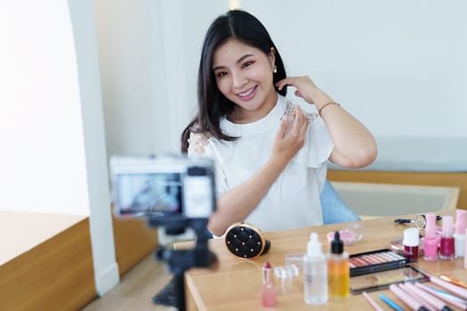 online trading business, a beautiful young woman working independently at home reviewing cosmetic products through the camera to customers to increase their interest in making a purchase decision.