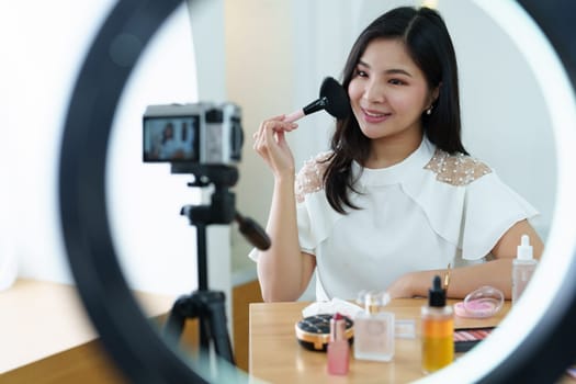 online trading business, a beautiful young woman working independently at home reviewing cosmetic products through the camera to customers to increase their interest in making a purchase decision.