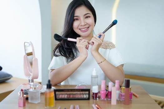 online trading business, a beautiful young woman working independently at home reviewing cosmetic products through the camera to customers to increase their interest in making a purchase decision.