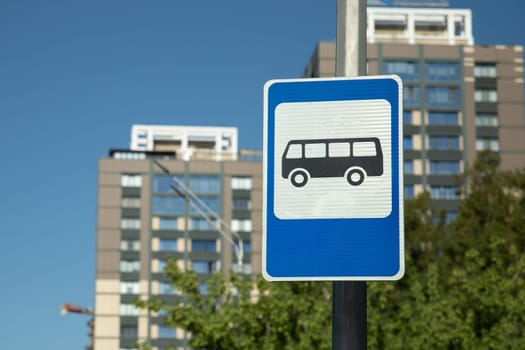 Blue bus stop sign on the background of a residential complex.