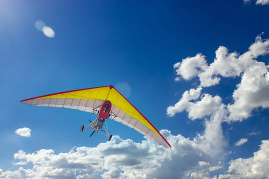 Motorized steerable paraglider flies in the sky, view from below.