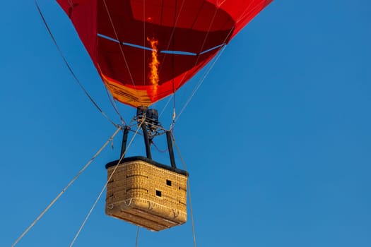 Empty basket from a red balloon against a clear blue sky.