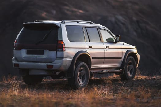 Off-road crossover car standing on mountain terrain at sunset. Travel and adventures 4wd suv.