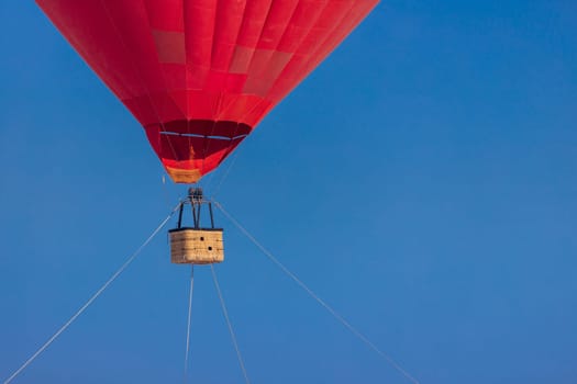 Empty basket from a red aerostat against a clear blue sky, copy space.