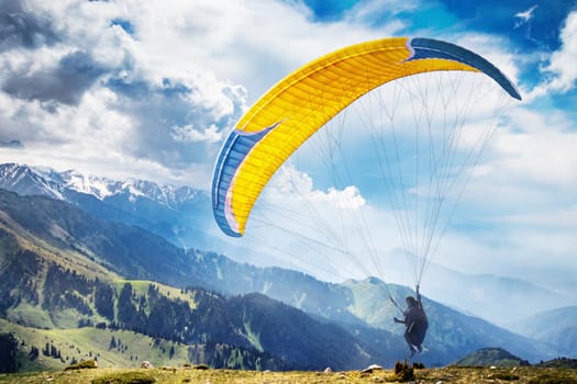 Amazing mountains landscape with a flying paraglider.