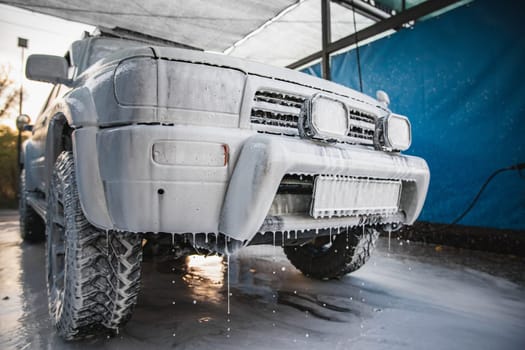 Car cleaning with foam. Wash white car with soap on car-wash self service.