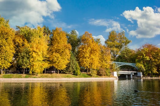 Autumn time on the Almaty Lake in Gorky Park, the foliage on the trees turned red and yellow. Almaty, Kazakhstan - October 14, 2022