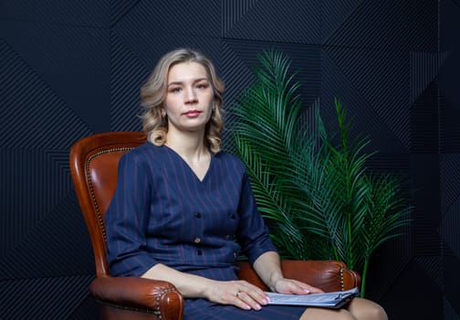 Portrait of a successful female psychologist in her office, notebook in hand, in her chair