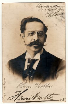 AMSTERDAM, THE NETHERLANDS - MAY 14, 1903: Vintage photo shows man wears glasses and moustache. Antique black white photography. Image contains handwriting.