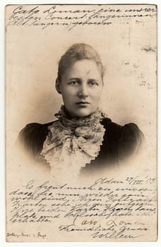 AMSTERDAM, THE NETHERLANDS - MARCH 27, 1903: Vintage photo shows woman wears scarf. Used postcard contains handwriting. Rich stain and paper details. Can be used as background.