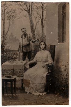 GERMANY - CIRCA 1920s: Vintage photo shows young woman and her injured (broken arm) boyfriend. Photography with sepia effect.