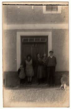 THE CZECHOSLOVAK REPUBLIC - CIRCA 1920s: Vintage photo shows a rural family in front of house. Photography contains slight blurriness.