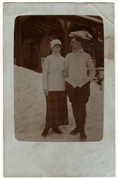THE CZECHOSLOVAK REPUBLIC - CIRCA 1930s: Vintage photo shows a couple poses in front of chalet during winter time. Man and woman stay on snow.