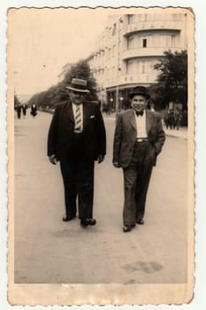 LAZNE PODEBRADY, THE CZECHOSLOVAK REPUBLIC - CIRCA 1940s: Vintage photo shows the elegant men at the spa resort. They wear hats and slack suits. Colonnade is on background.