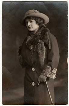 FRANKFURT AM ODER, GERMANY - 1913: Vintage photo shows a young elegant woman wears hat, fur scarf and coat. Black white studio photography.