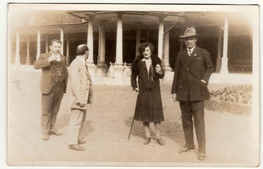 KARLOVY VARY, THE CZECHOSLOVAK REPUBLIC - CIRCA 1930s: Vintage photo shows the elegant men and woman at the spa resort. Men wear slack suits. Colonnade is on background.