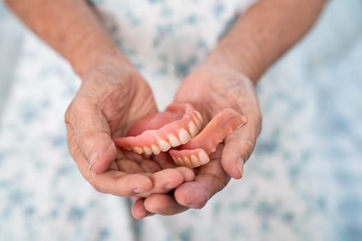 Asian elderly woman patient holding to use denture, healthy strong medical concept.