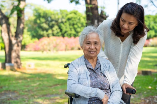 Caregiver help and care Asian elderly woman use walker with strong health while walking at park in happy fresh holiday.