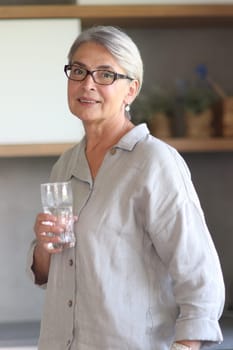 mature woman smiling close up in the office holding a glass of water