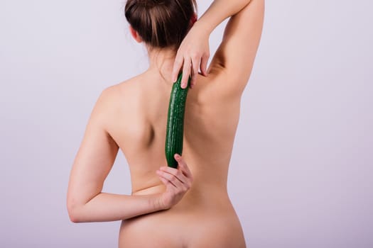 Close up portrait of an attractive young woman topless with cucumber in studio