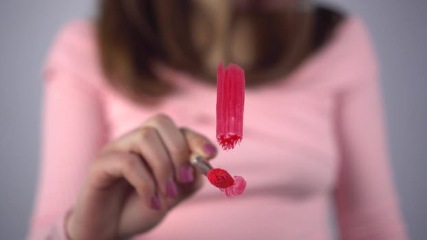 A young woman draws an exclamation mark on the glass. A girl in a pink sweater draws with a brush and red paint. Close-up. 4k