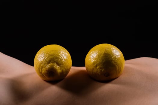 Young woman with cellulite problem and lemon on a dark background, closeup