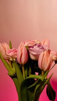 A close-up vertical plan of a summer pink bouquet of flowers. Tulips and roses on a neon background with copy space, paste text