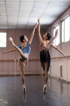 Two Asian ballerinas are dancing in the class