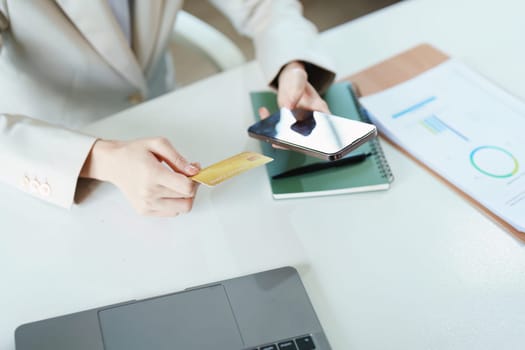 Portrait of young Asian woman using credit card and phone for online shopping.