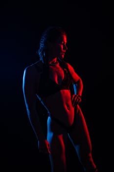 Young woman in underwear is in a studio with neon lights.