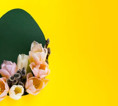 Creative Easter layout with fresh tulip flowers and leaves on bright yellow and green paper background. Spring natural concept. Shape in the form of an egg.