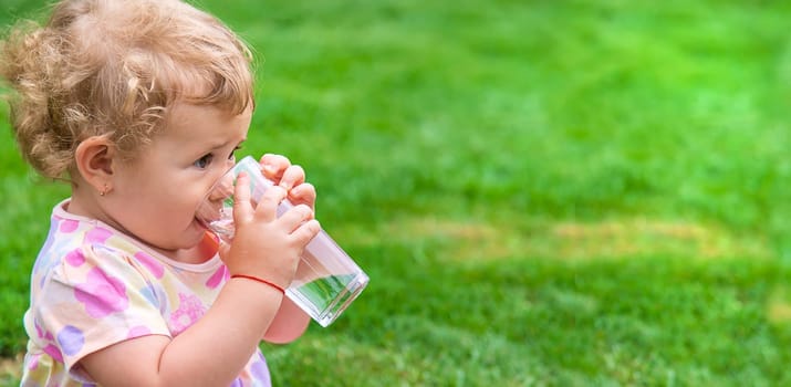 Baby drinks water from a glass. Selective focus. Child.