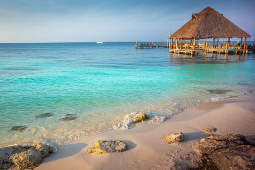 Cancun beach with rustic Gazebo palapa pier at sunset, Riviera Maya, Mexican Caribbean