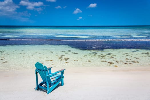 Adirondack Chair and secluded eagle beach on Aruba island at sunny day, Caribbean sea