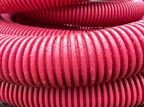 pile of plastic pipes wet from the rain, corrugated burgundy pipes, magenta abstract texture background, color of the year, High quality photo