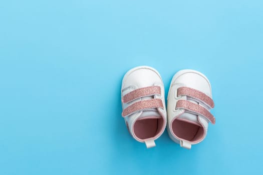 Tiny newborn baby shoes on paper background with copy space. Baby clothes concept. Top view, flat