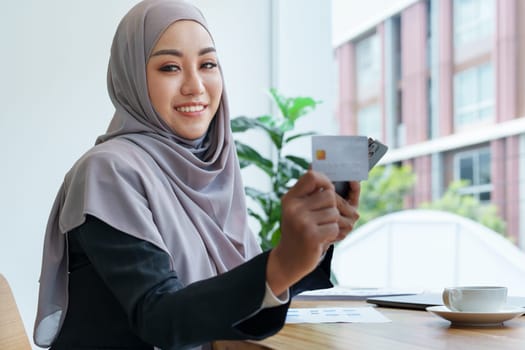 Beautiful Muslim woman shopping online using her phone and credit card.