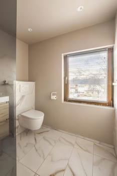 a bathroom with a toilet and sink in the corner, looking out to the outside from behind it is an open window