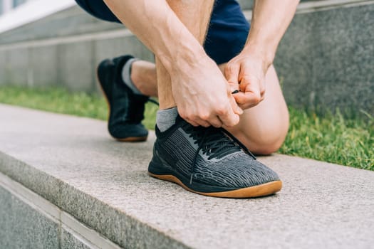 Close up sports man tying shoelace while running outdoors.