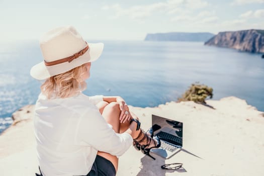 Happy girl doing yoga with laptop working at the beach. beautiful and calm business woman sitting with a laptop in a summer cafe in the lotus position meditating and relaxing. freelance girl remote work beach paradise