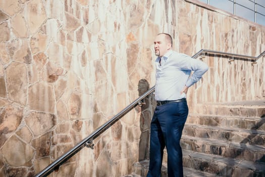 Portrait of a senior professional man in a suit with various problems. A middle-aged businessman with a briefcase descends the stairs.