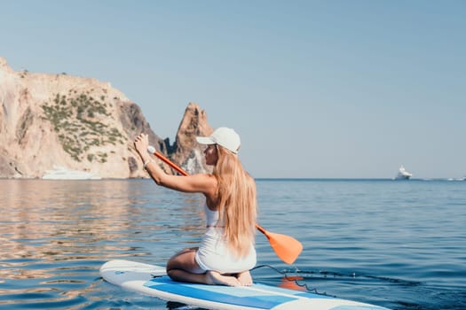 Close up shot of beautiful young caucasian woman with black hair and freckles looking at camera and smiling. Cute woman portrait in a pink bikini posing on a volcanic rock high above the sea