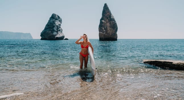 Close up shot of beautiful young caucasian woman with black hair and freckles looking at camera and smiling. Cute woman portrait in a pink bikini posing on a volcanic rock high above the sea