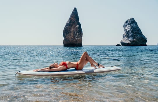 Close up shot of beautiful young caucasian woman with black hair and freckles looking at camera and smiling. Cute woman portrait in a pink bikini posing on a volcanic rock high above the sea