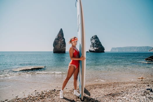 Close up shot of beautiful young caucasian woman with black hair and freckles looking at camera and smiling. Cute woman portrait in a pink bikini posing on a volcanic rock high above the sea