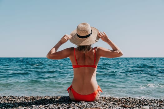 Woman travel sea. Young Happy woman in a long red dress posing on a beach near the sea on background of volcanic rocks, like in Iceland, sharing travel adventure journey