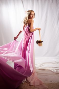 Portrait of cute kid girl posing in pink beautiful dress on white background. Model in studio looking as gentle magic princess from fairy taly having photo shoot on white background